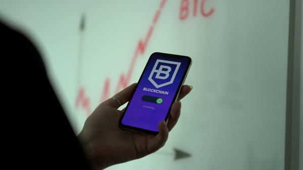 Smartphone showing a blockchain application connecting next to a rising price chart