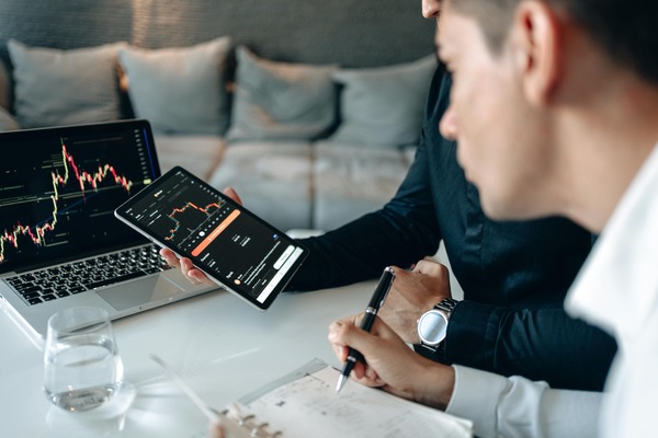 Trader reviewing cryptocurrency price charts on a laptop and tablet